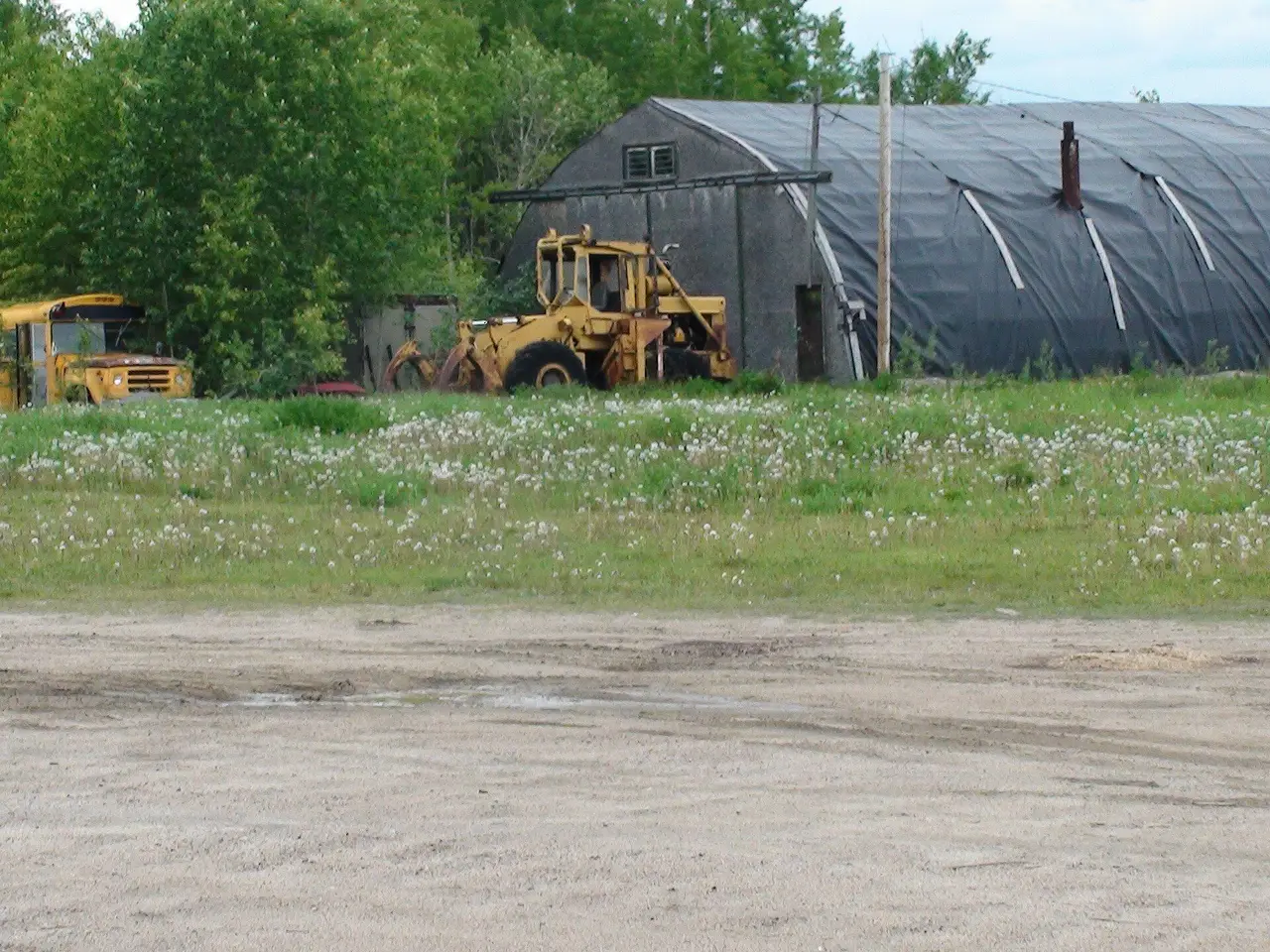 Old loader and school bus by a quonset shed, 2019