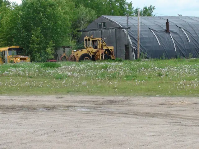 Old loader and school bus by a quonset shed